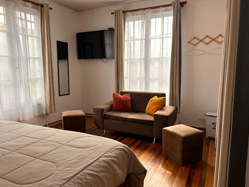ein Schlafzimmer mit einem Bett, einem Stuhl und einem TV in der Unterkunft Casona Lorena in Santiago