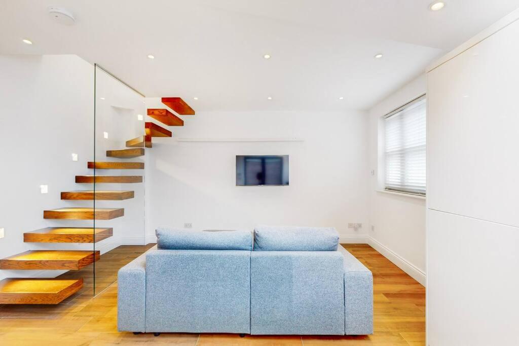 a living room with a blue couch and a staircase at 1 Bed House with Garden sleeps 4 - 10 min to Station in London