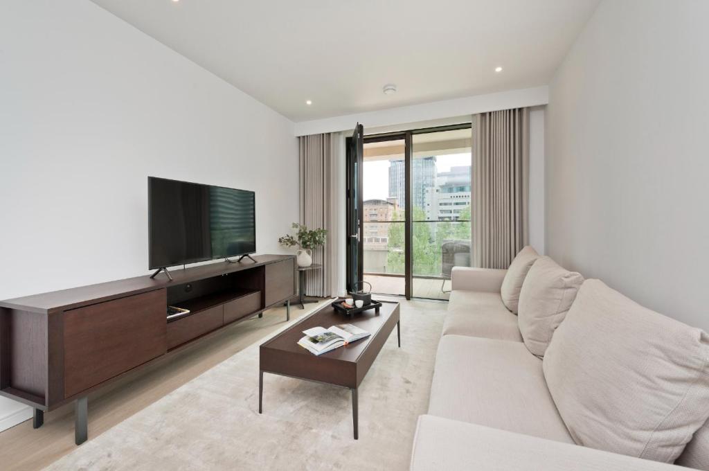 Elegant and Modern Apartments in Canary Wharf right next to Thames في لندن: غرفة معيشة مع أريكة وتلفزيون بشاشة مسطحة