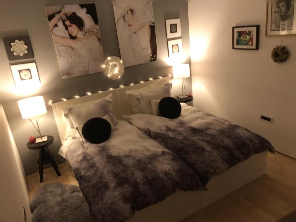 a bedroom with a bed and two lamps and pictures on the wall at Red & Black Apartment in Zagreb