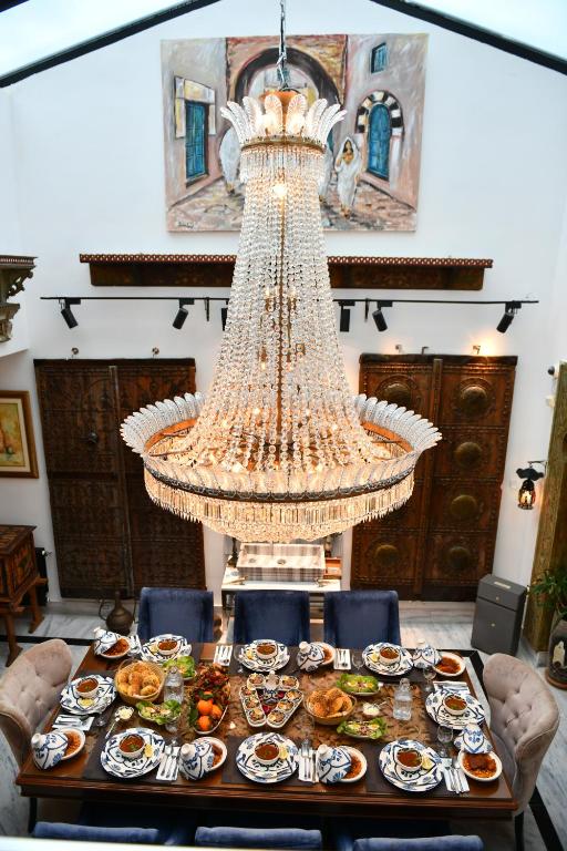 ein großer Kronleuchter hängt über einem Tisch mit Teller mit Lebensmitteln in der Unterkunft Dar Al Makam - Adult Only in Soliman