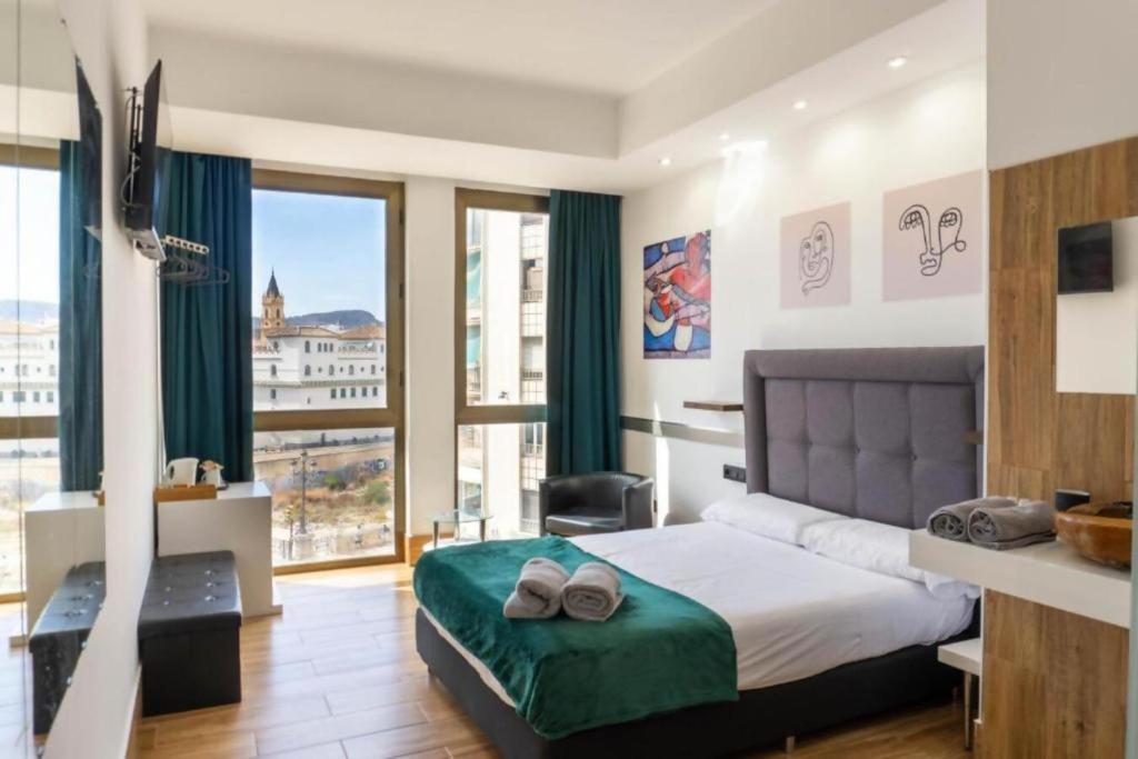 ein Schlafzimmer mit einem Bett und einem großen Fenster in der Unterkunft Ilustre Rooms by Beehive Vacances in Málaga