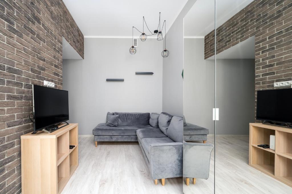 ein Wohnzimmer mit einem Sofa und einem TV in der Unterkunft Piotrkowska Modern Apartment in Łódź