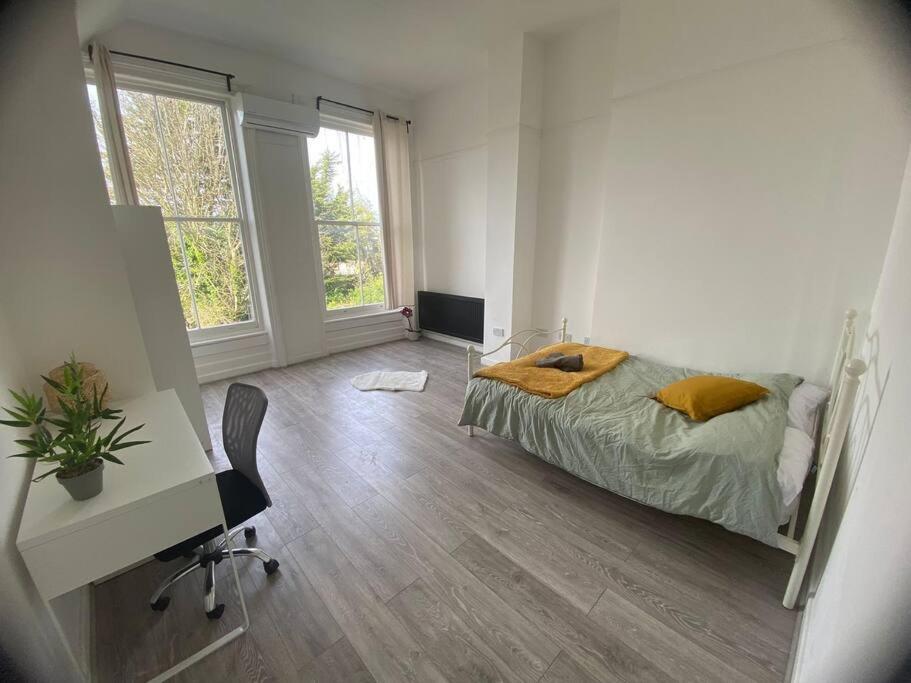 a bedroom with a bed and a desk and window at Stunning executive apartment. in London