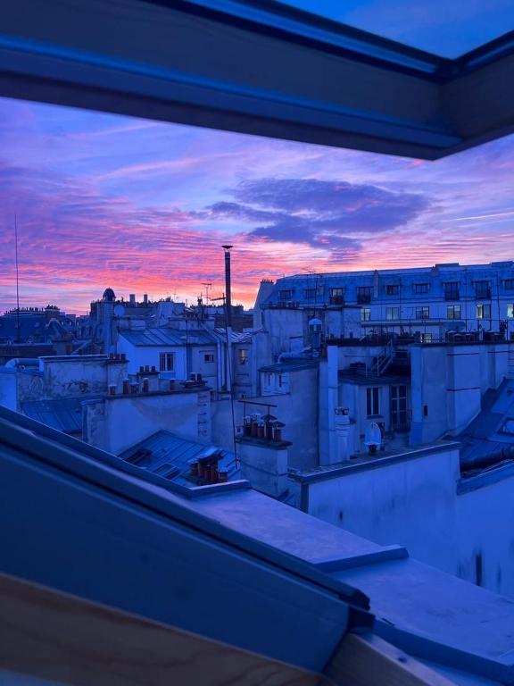 d'un balcon offrant une vue sur la ville au coucher du soleil. dans l'établissement Ravissant studio parisien, à Paris