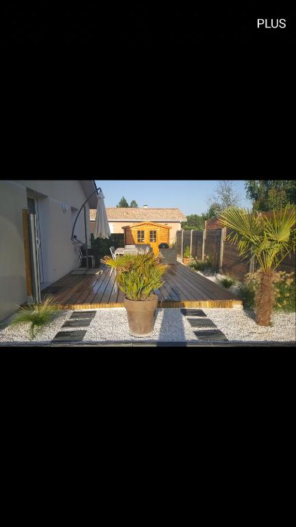 une terrasse avec deux plantes en pot et une maison dans l'établissement maison de vacances Lège-cap-ferret, à Lège-Cap-Ferret