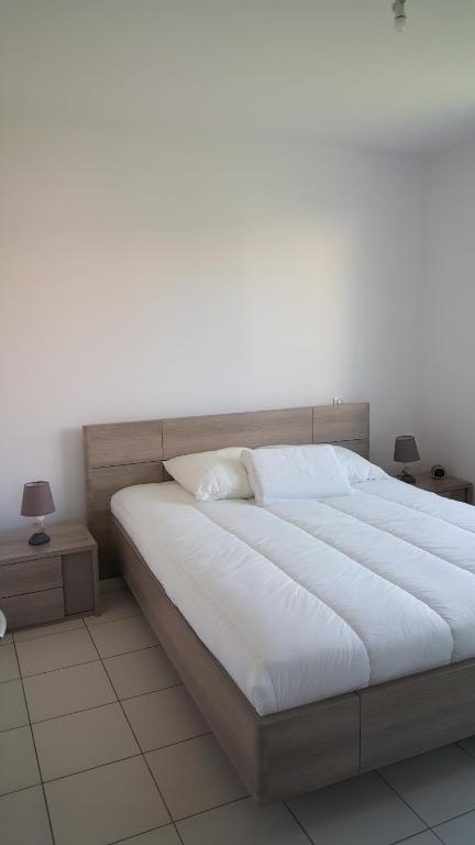 a large bed in a bedroom with two tables at maison de vacances Lège-cap-ferret in Lège-Cap-Ferret