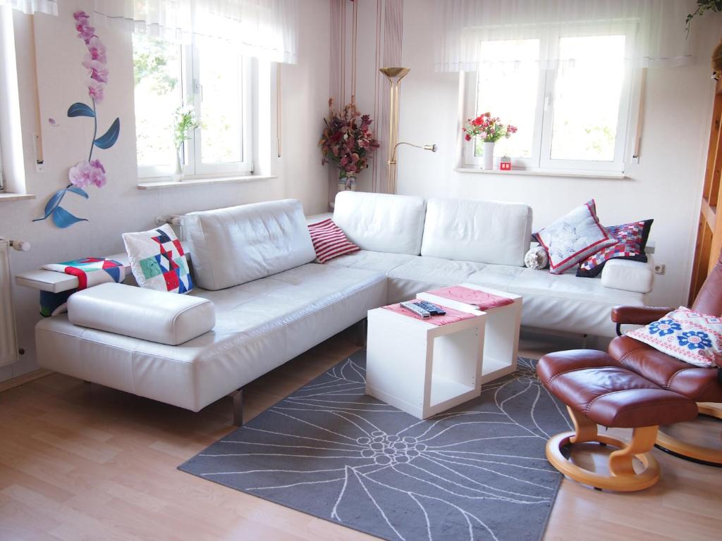 uma sala de estar com um sofá branco e duas cadeiras em Ferienwohnung am Domberg em Suhl