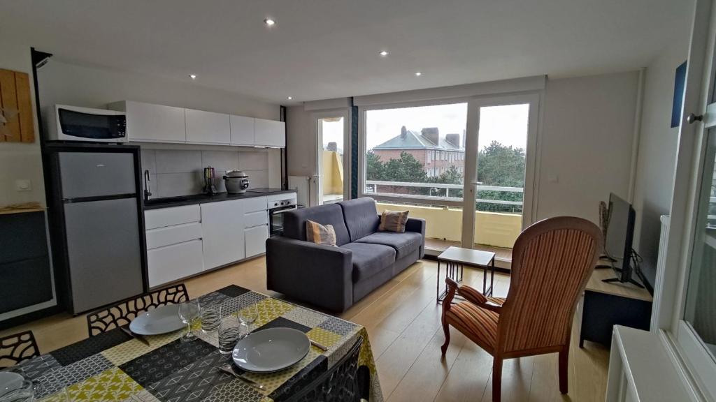 un salon avec un canapé, une table et une cuisine dans l'établissement Détente au gré des marées, à Berck-sur-Mer