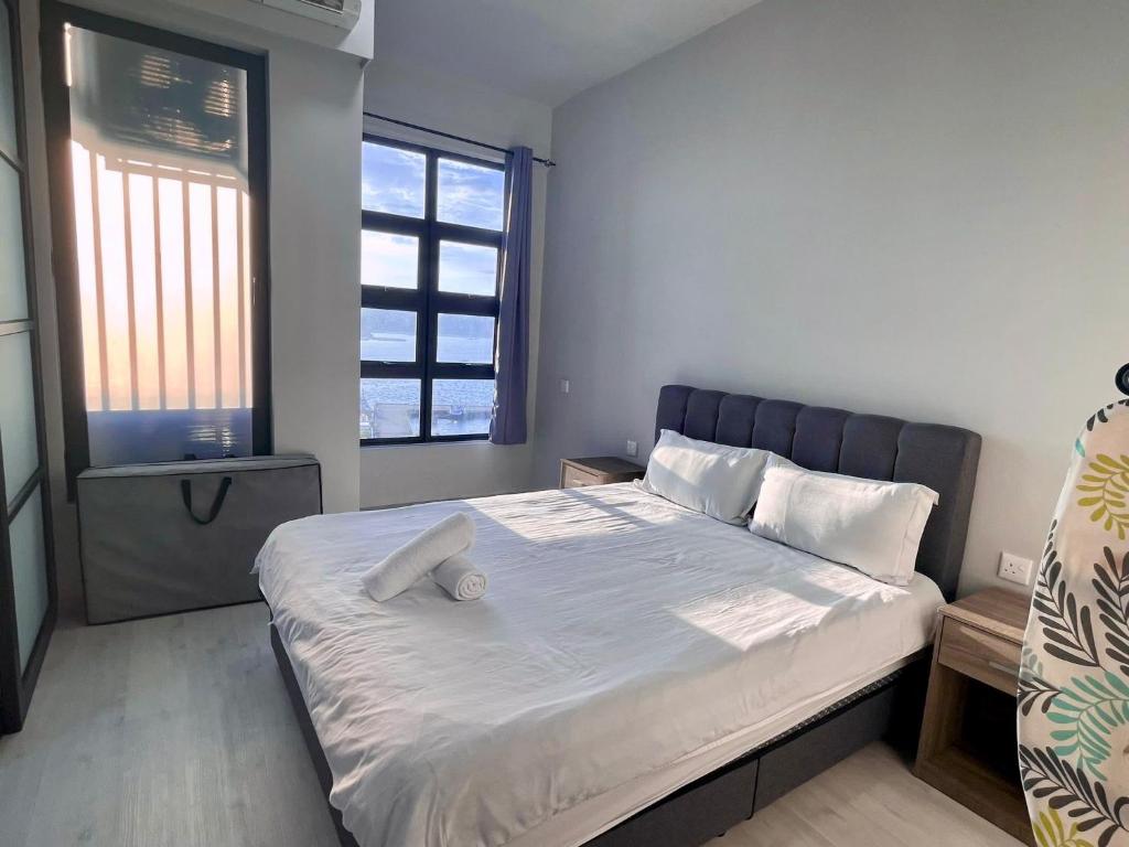 a bedroom with a large bed with white sheets and pillows at SUNRISE JESSELTON QUAY NEAR SURIA GAYA STREET Jesselton Point in Kota Kinabalu