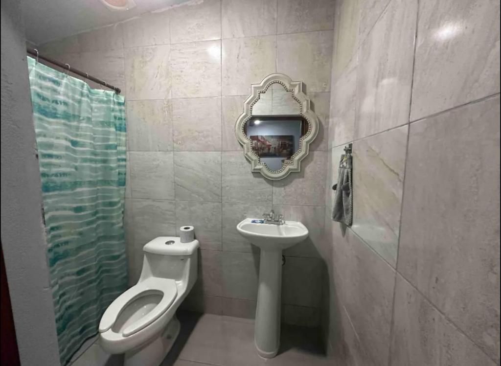 uma casa de banho com um WC, um lavatório e um espelho. em PATO´S em Ciudad Victoria
