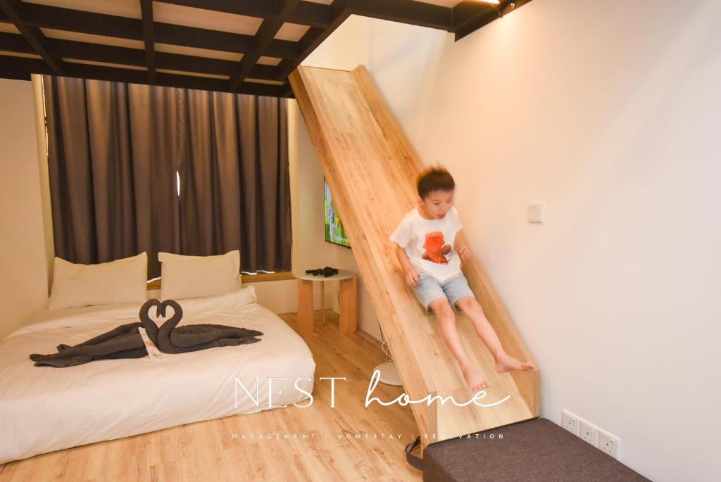 Sunway Grid Loft Suite by Nest Home【Olympic Size Pool】 في Kampong Pendas: صبي صغير يجلس على سلم في غرفة النوم