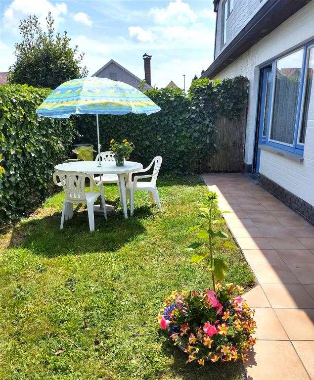 a table and chairs with an umbrella in the yard at Sirenetta in De Haan