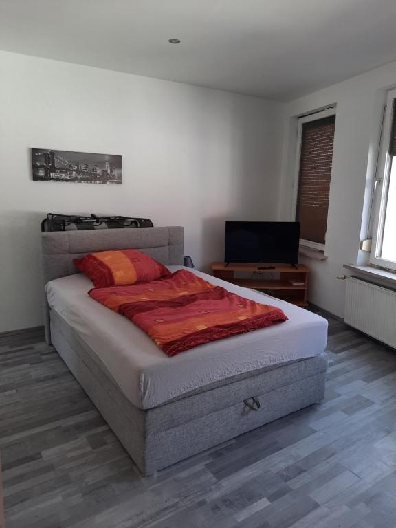 um quarto com uma cama e uma televisão de ecrã plano em Gästehaus-City em Helmstedt