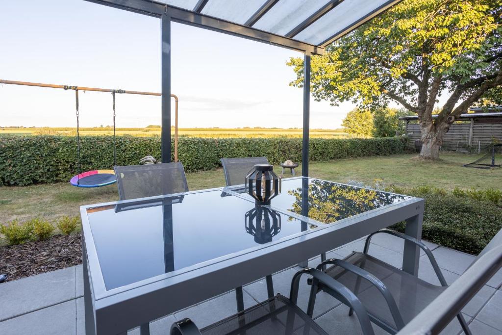 a glass table and chairs on a patio at Ferienhaus Robbenglück OG in Butjadingen OT Tossens