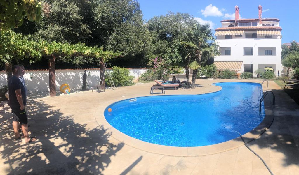 a man is standing next to a swimming pool at Green Villa in Banjole