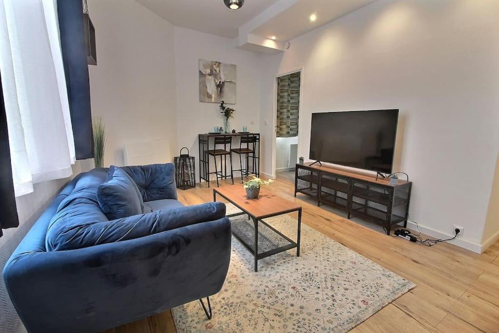 un salon avec un canapé bleu et une télévision à écran plat dans l'établissement Le Cocon De Pleyel, à Saint-Denis