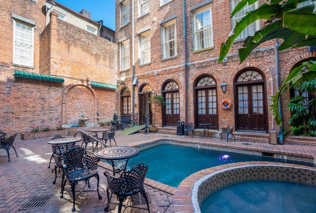 een binnenplaats met een zwembad en tafels en stoelen bij Quarter House Suites in New Orleans