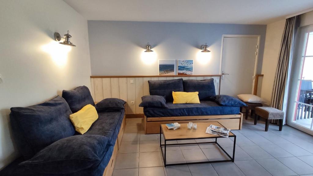 - un salon avec deux canapés bleus et une table basse dans l'établissement Argousiers 107, à Fort-Mahon-Plage