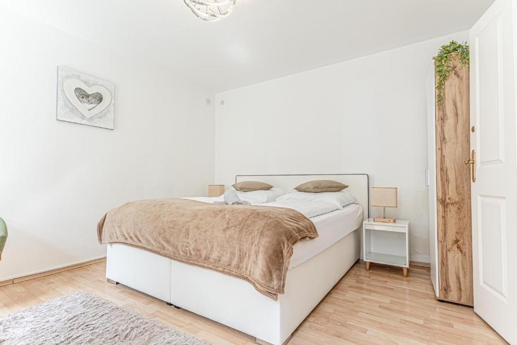 um quarto branco com uma cama branca e piso em madeira em City Vibes: 1BR Apt, 10 Min to Westbahnhof em Viena