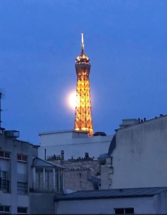 une tour illuminée posée au sommet d'un immeuble dans l'établissement Vue Tour Eiffel - calme & chic, à Paris