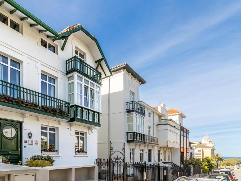 una fila de casas blancas con balcones verdes en Gran casa familiar al lado de la playa en Santander