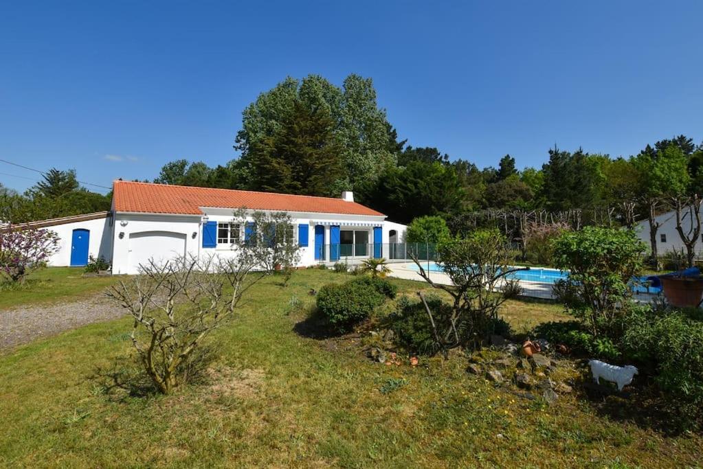 a white house with blue doors and a yard at « La tranquillité » Villa avec piscine in Saint-Hilaire-de-Riez