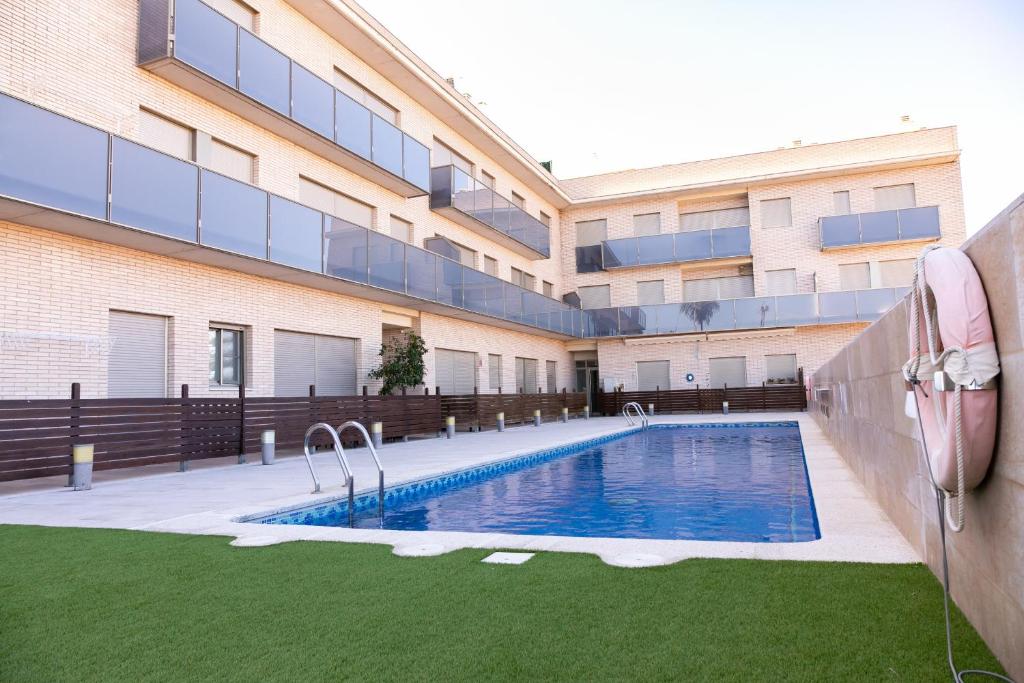 uma piscina em frente a um edifício em ALBOSCRIU - Duplex con piscina y barbacoa em Deltebre