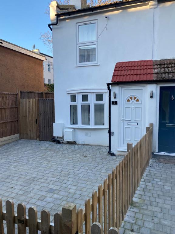 une maison blanche avec une porte bleue et une clôture dans l'établissement 2Philipot, à Eltham