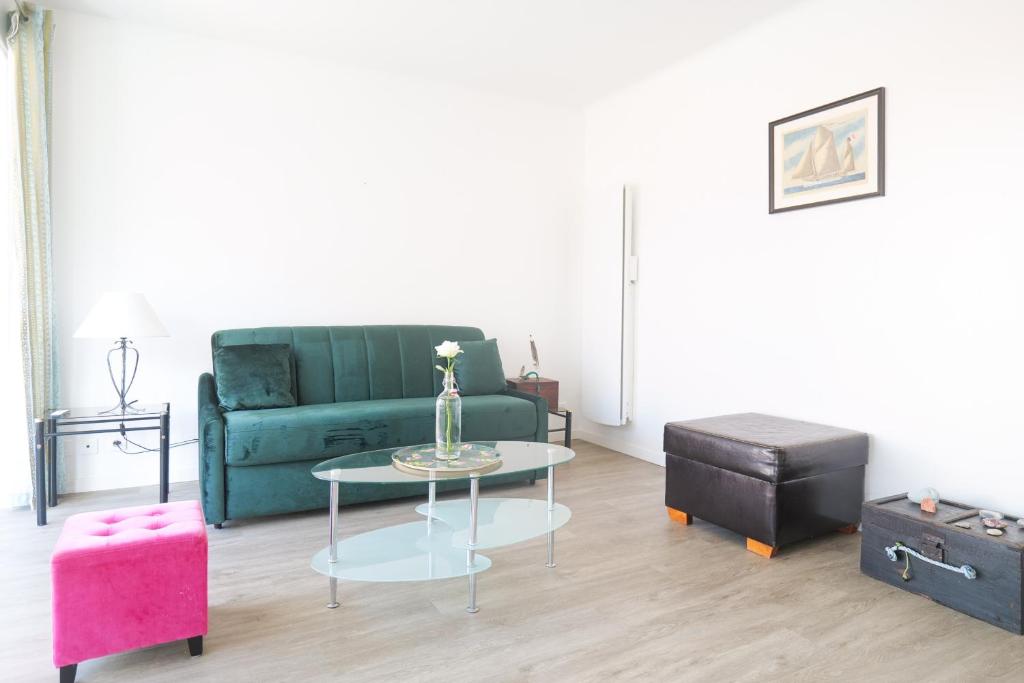 un salon avec un canapé vert et une table dans l'établissement Appartement proche océan Les Sables d'Olonne 4 personnes, à Les Sables-dʼOlonne