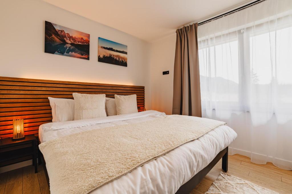 Un dormitorio con una cama grande y una ventana en Albert Residence Grand Chalet & SPA Poiana Brașov en Poiana Brasov
