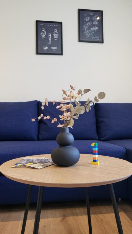 a blue couch with a table with a vase on it at Lego Fans Аpartment #1 in Billund Center in Billund