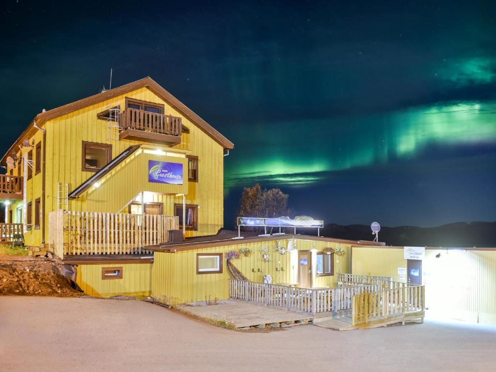 a yellow building with the aurora in the sky at Abisko Guesthouse & Activities in Abisko