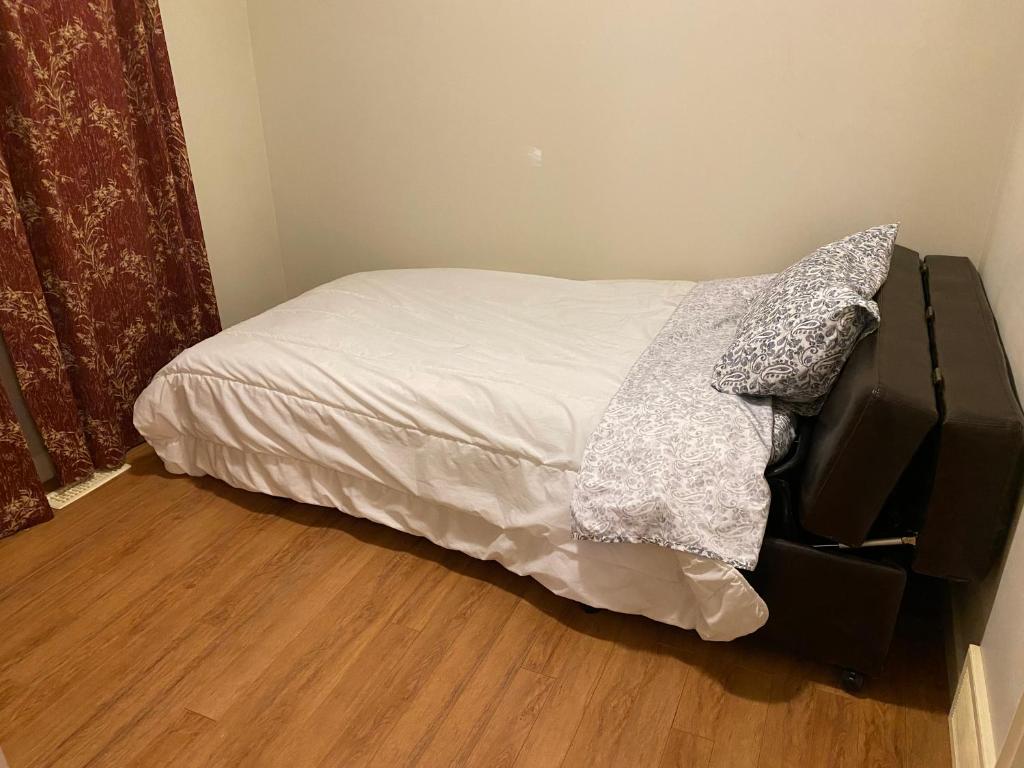 a bedroom with a bed with a white sheets and a television at Small Cozy Room in Calgary