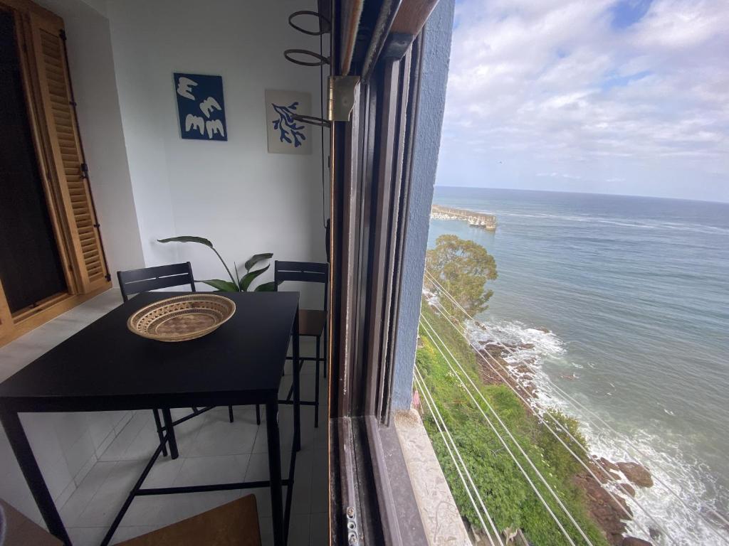 a room with a table and a view of the ocean at Durmiendo con el mar in Lastres