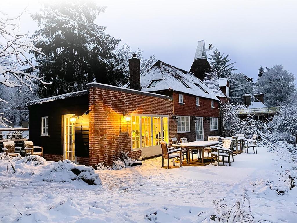 Mousehall Oast في Wadhurst: منزل به طاولة وكراسي في الثلج