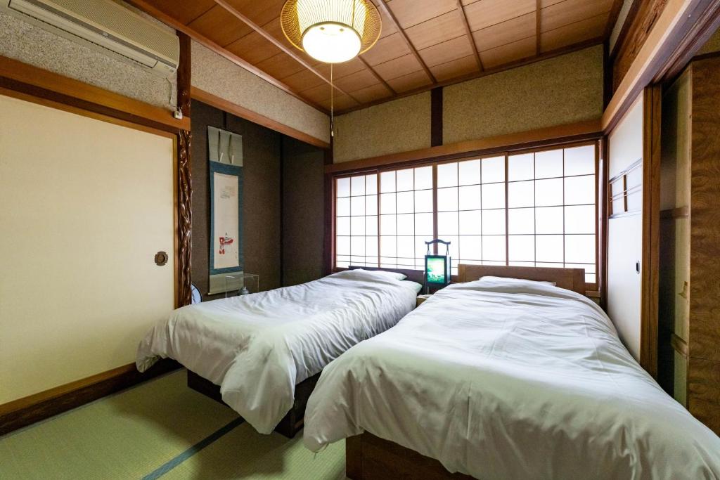 two twin beds in a room with two windows at ゲストハウス　luluha in Awatabe