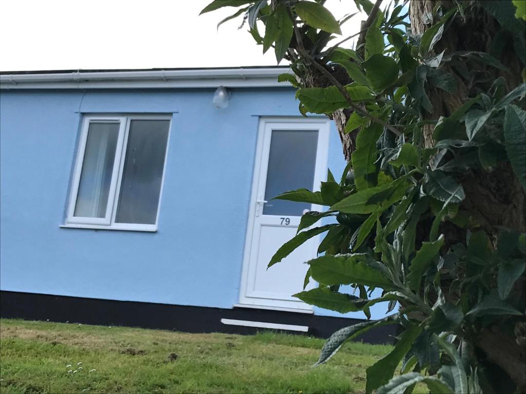 a blue house with a window and a tree at Brixham Holiday Park Silver Albatross - Pet Friendly in Brixham