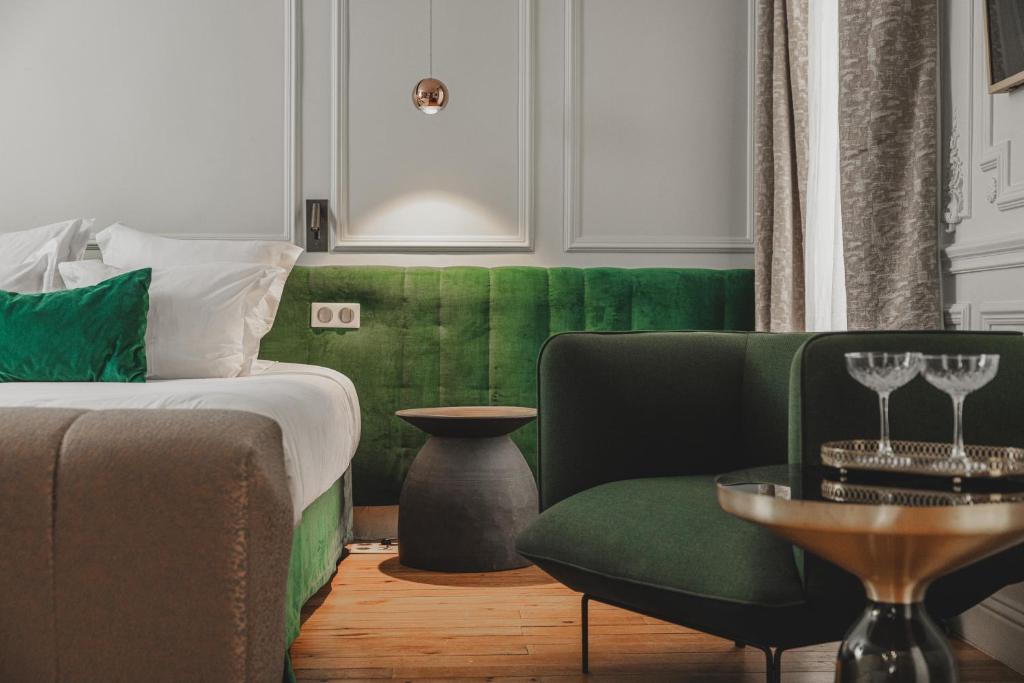a bedroom with a green couch and a green chair at Hôtel Singulier Bordeaux - Boutique Hôtel & Spa Anne Semonin in Bordeaux