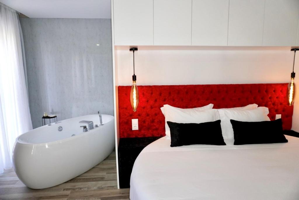 1 dormitorio con 1 cama grande y bañera en Lux'Otel City Lodge, en Barcelos