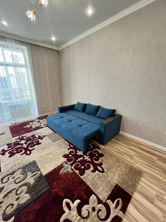 uma sala de estar com um sofá azul e um tapete em ЖК Грант Чемпион em Astana