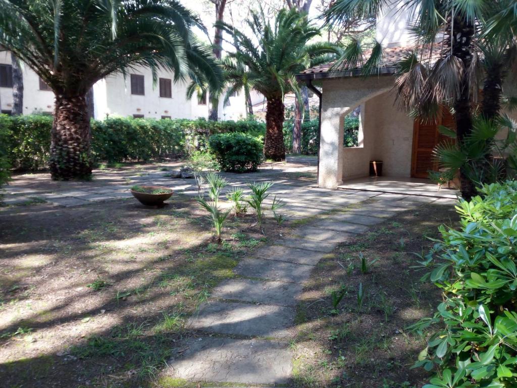 a courtyard with palm trees and a building at Villetta Pescespada in Grosseto