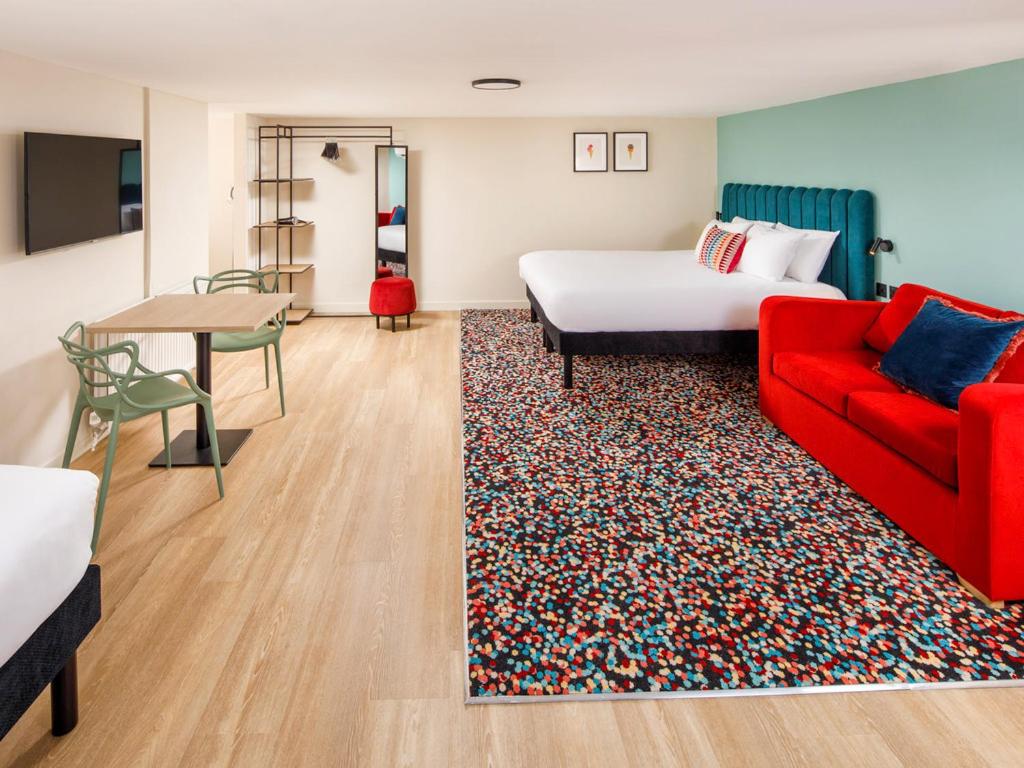une chambre d'hôtel avec un lit et un canapé rouge dans l'établissement Nq2 Collections, à Bournemouth
