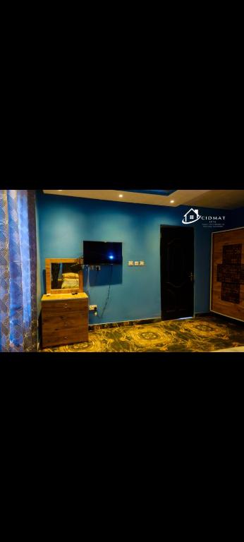 sala de estar con pared azul y TV en CIDMAT VILLA, en Freetown
