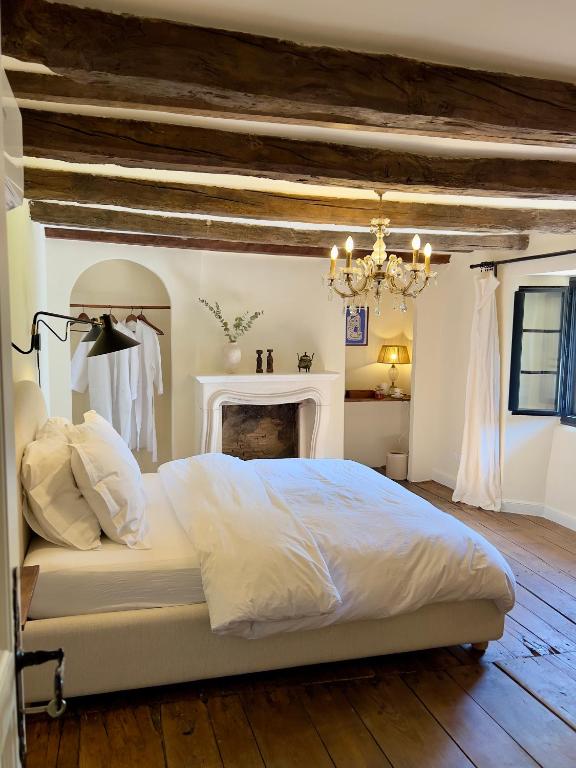 - une chambre avec un lit blanc et une cheminée dans l'établissement Maison G.H., à Champniers-et-Reillac
