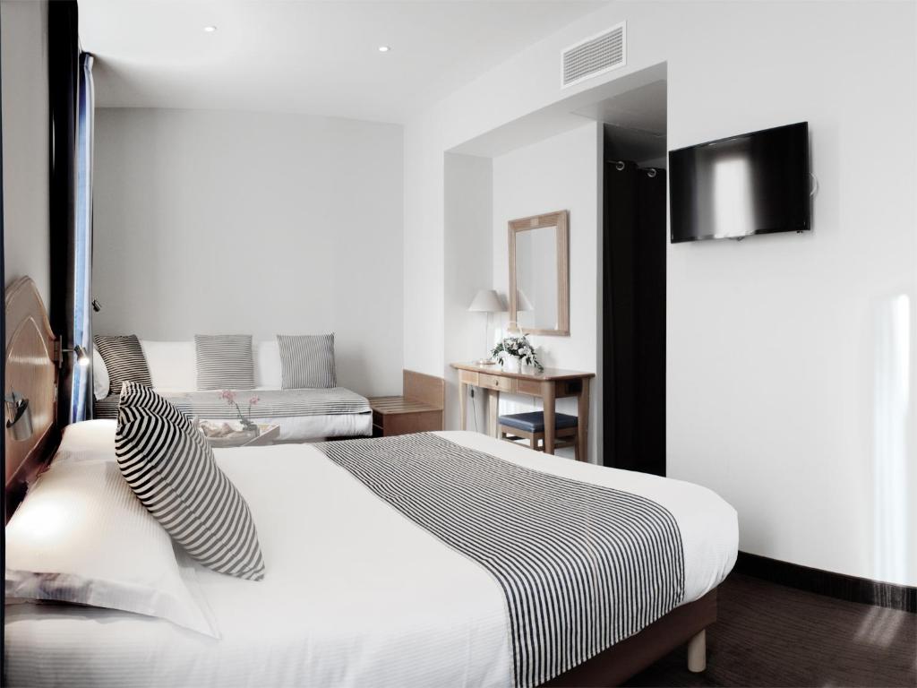 sypialnia z dużym białym łóżkiem z czarno-białymi poduszkami w obiekcie Hôtel Esprit d'Azur w Nicei