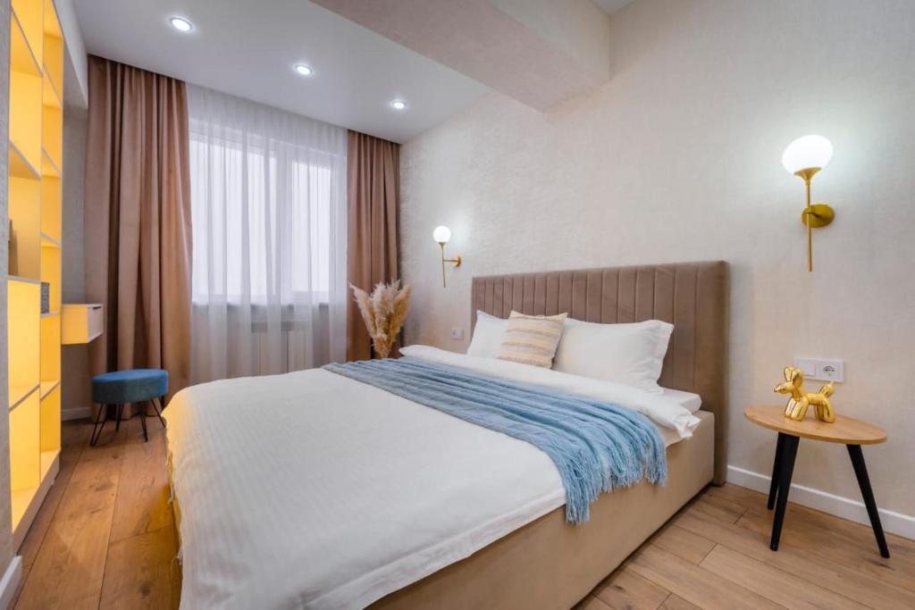 1 dormitorio con 1 cama grande con manta azul en Стильная квартира в центре города, en Almaty
