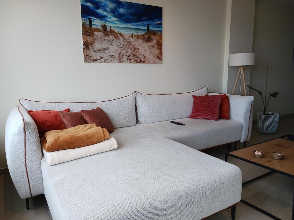 una sala de estar con un sofá blanco con almohadas rojas en Suite Betsy vlakbij het strand, en Ostende