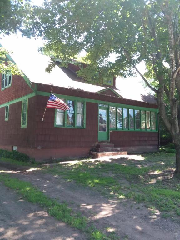 Uma casa de tijolos vermelhos com uma bandeira americana. em Hemlock House em Ironwood