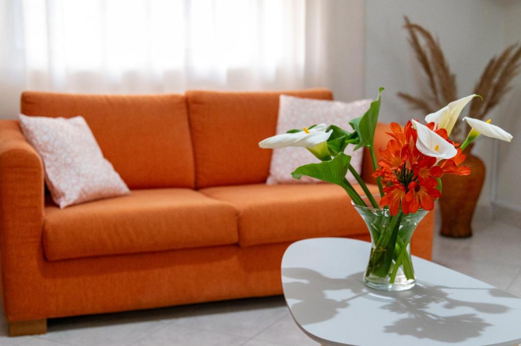 an orange couch with flowers in a vase on a table at 50 DANAIDES in Argos
